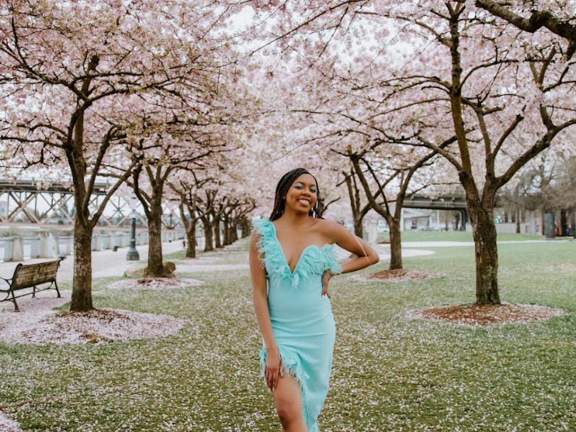 The writer in front of cherry blossom trees.