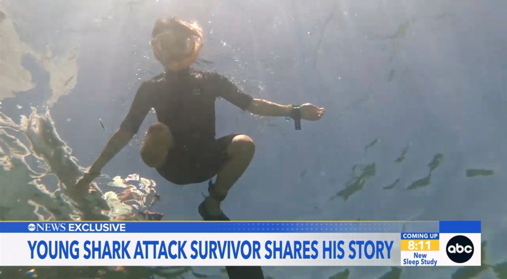 Boy in wetsuit underwater, sharing his story after a shark attack.