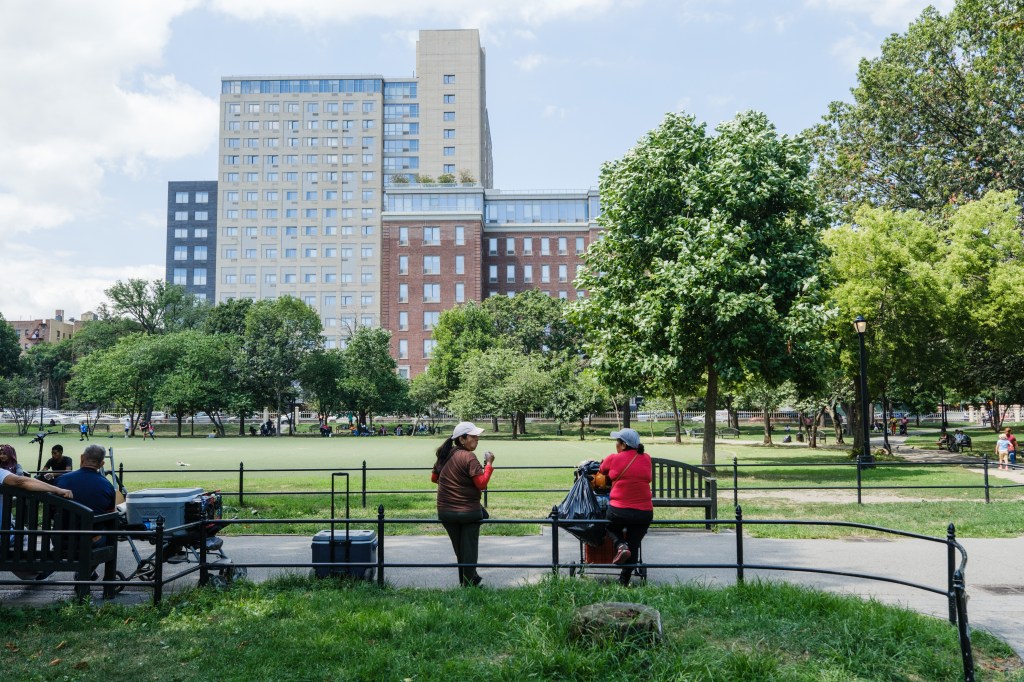 People relaxing in a park with buildings in the background.