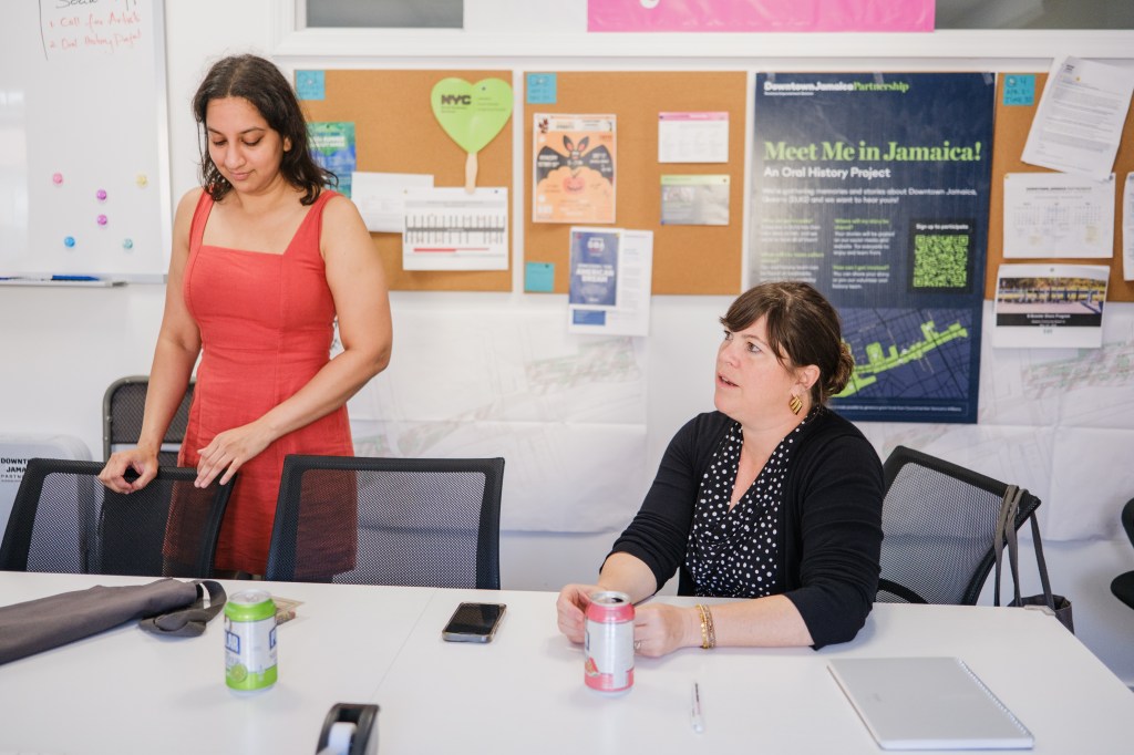 Two women sitting at a table discussing a project.