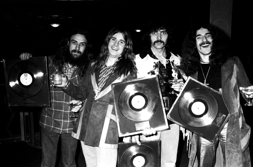 Black Sabbath members Geezer Butler, Tommy Iommi, Bill Ward and Ozzy Osbourne posing with gold discs.