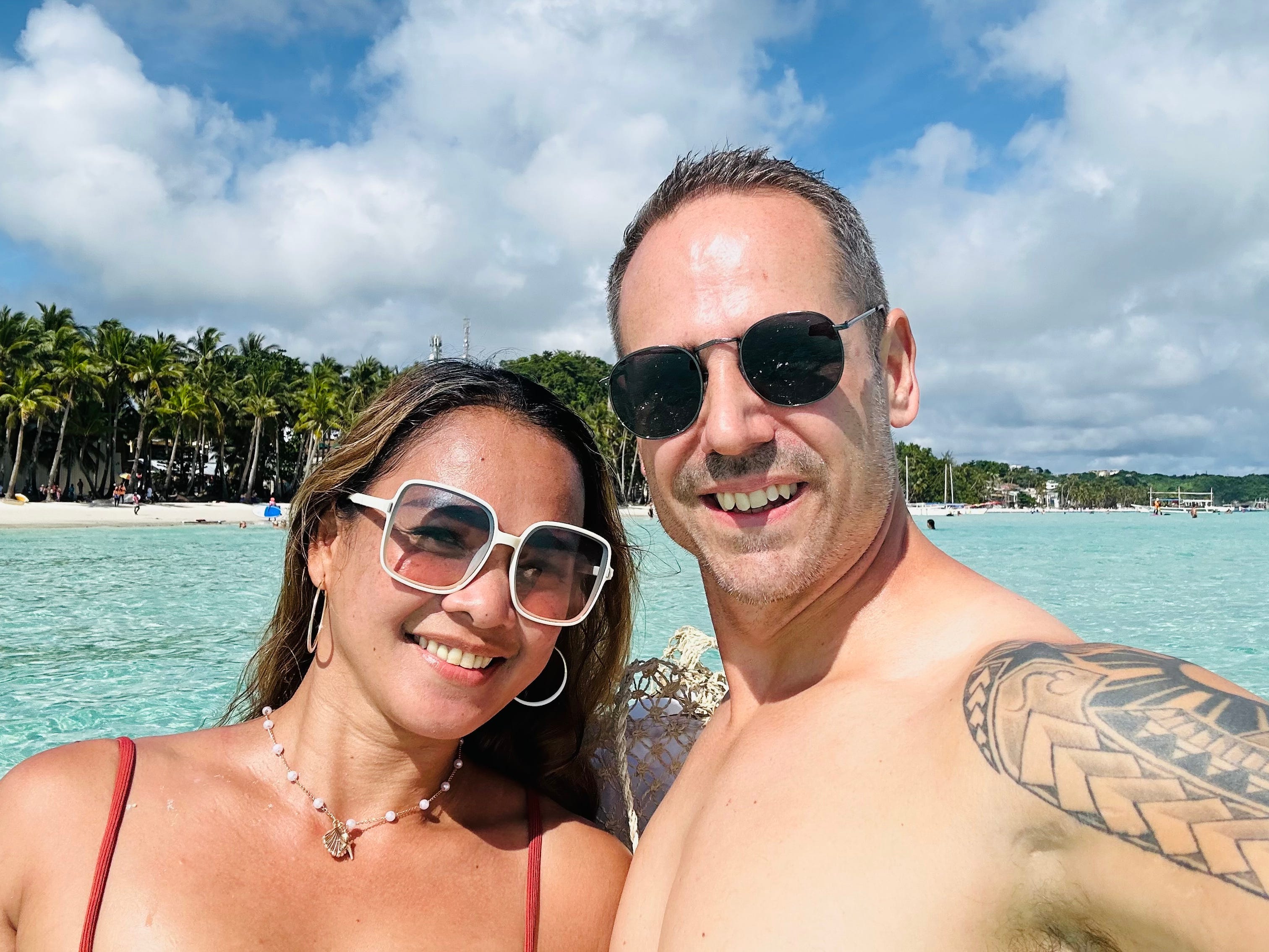 A man and a woman posing for a selfie in the ocean.