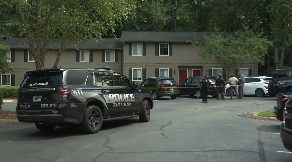 Police car and officers at an apartment complex following a shooting.