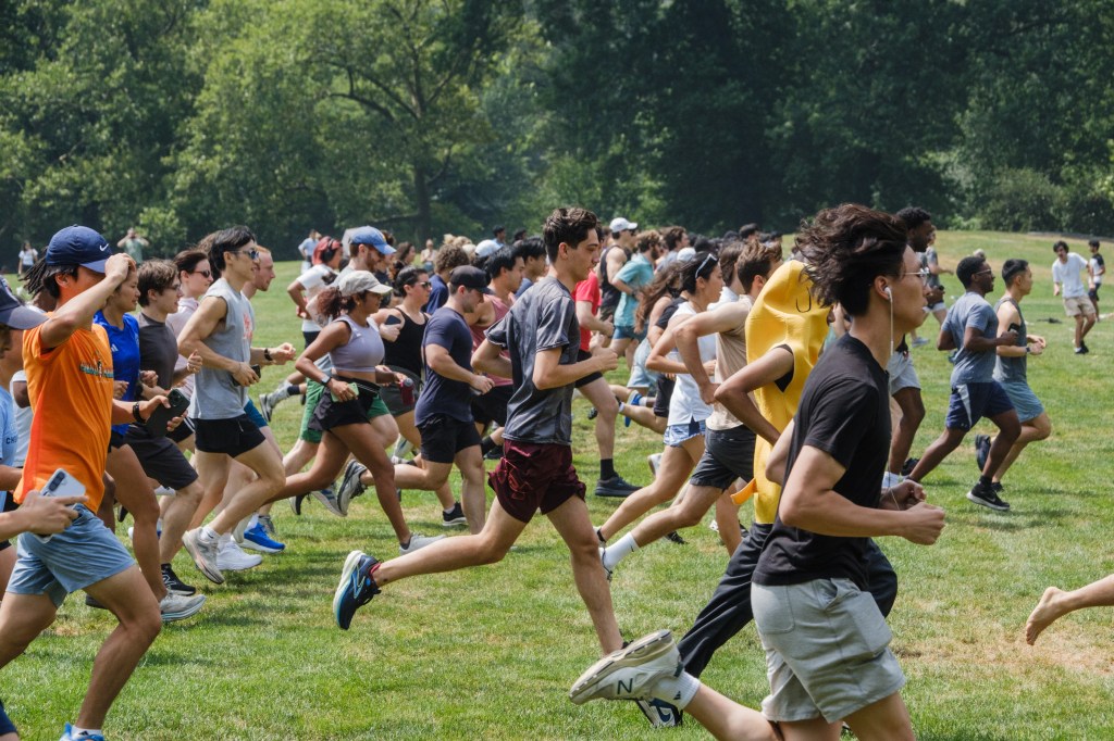 Large group of people running in a field.
