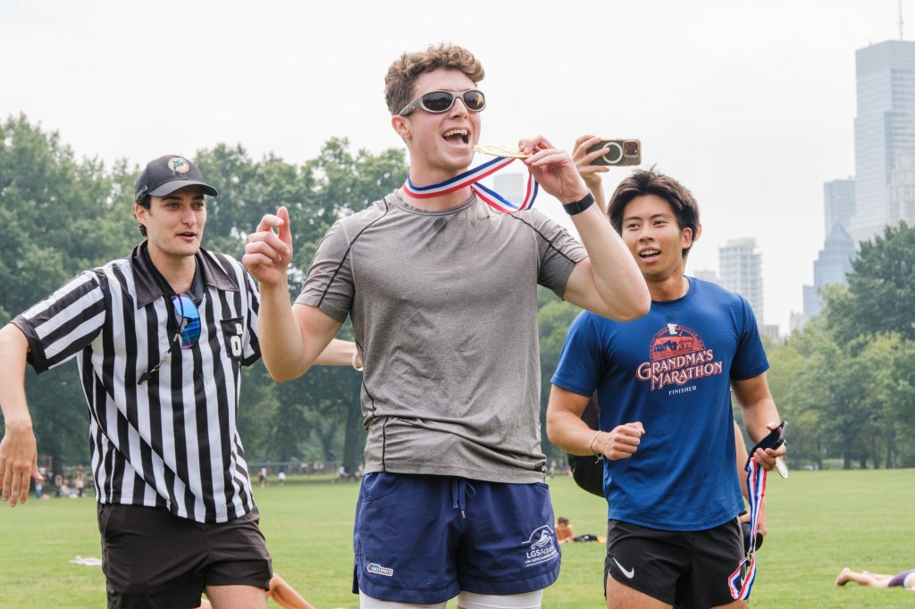 Runner holding a gold medal with friends.