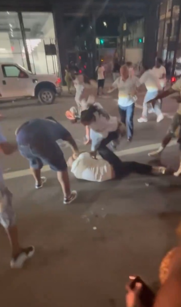 Footage of a fight where a person is lying on the ground being restrained by others.