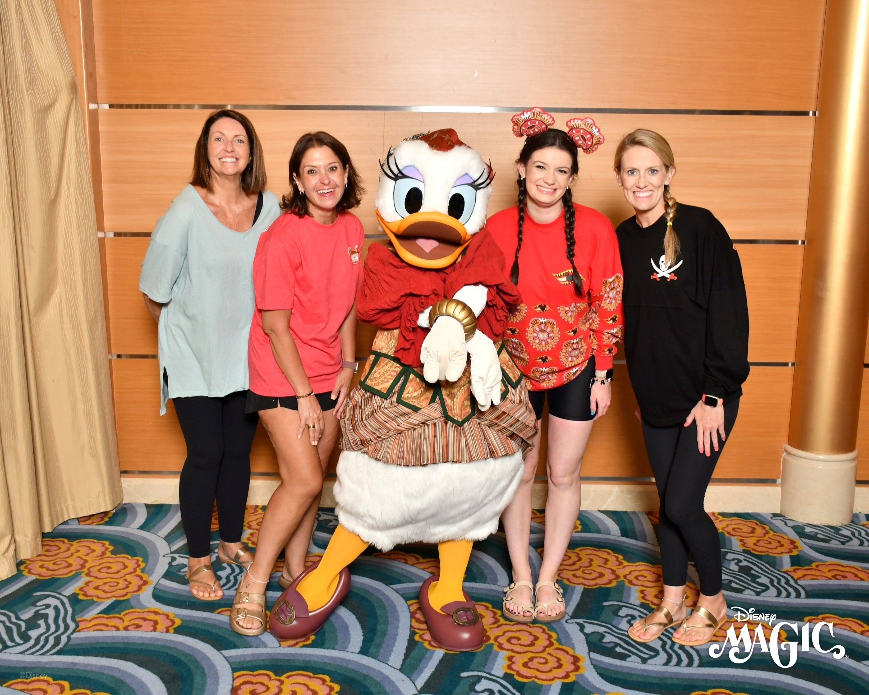 The author and three of her friends taking a photo with Daisy Duck on pirate night aboard the Disney Magic ship.