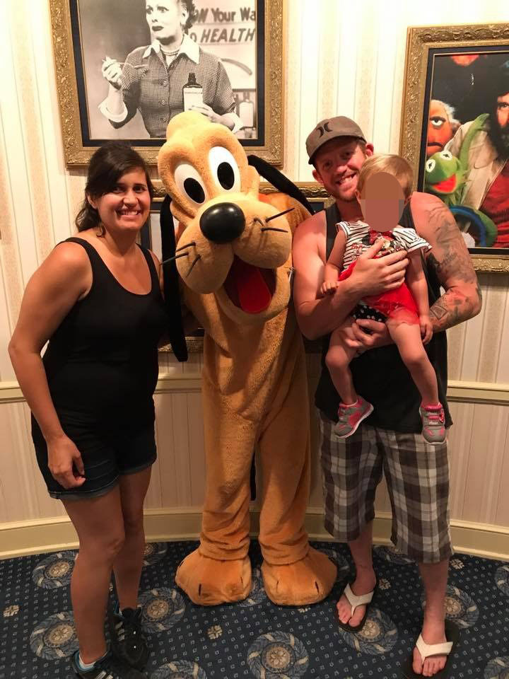 Photo of a family posing with Pluto at Disney.