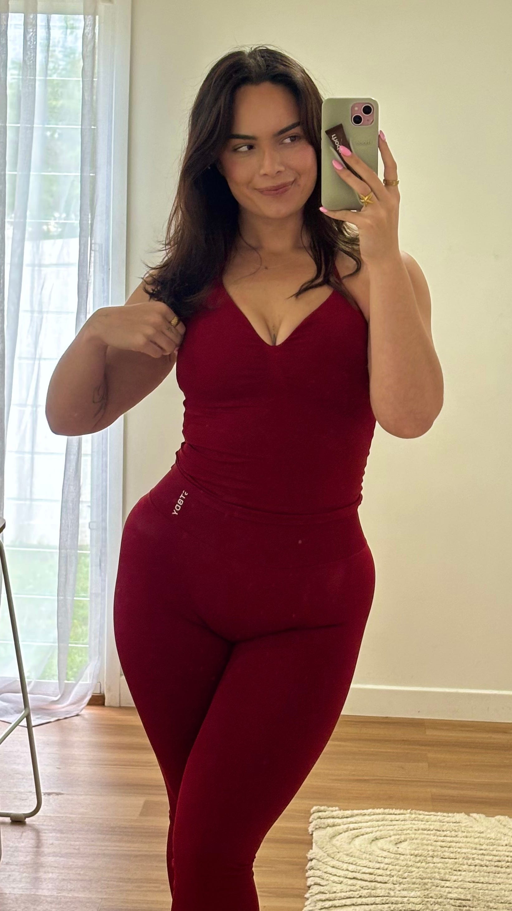 A woman takes a mirror selfie wearing gym clothes.