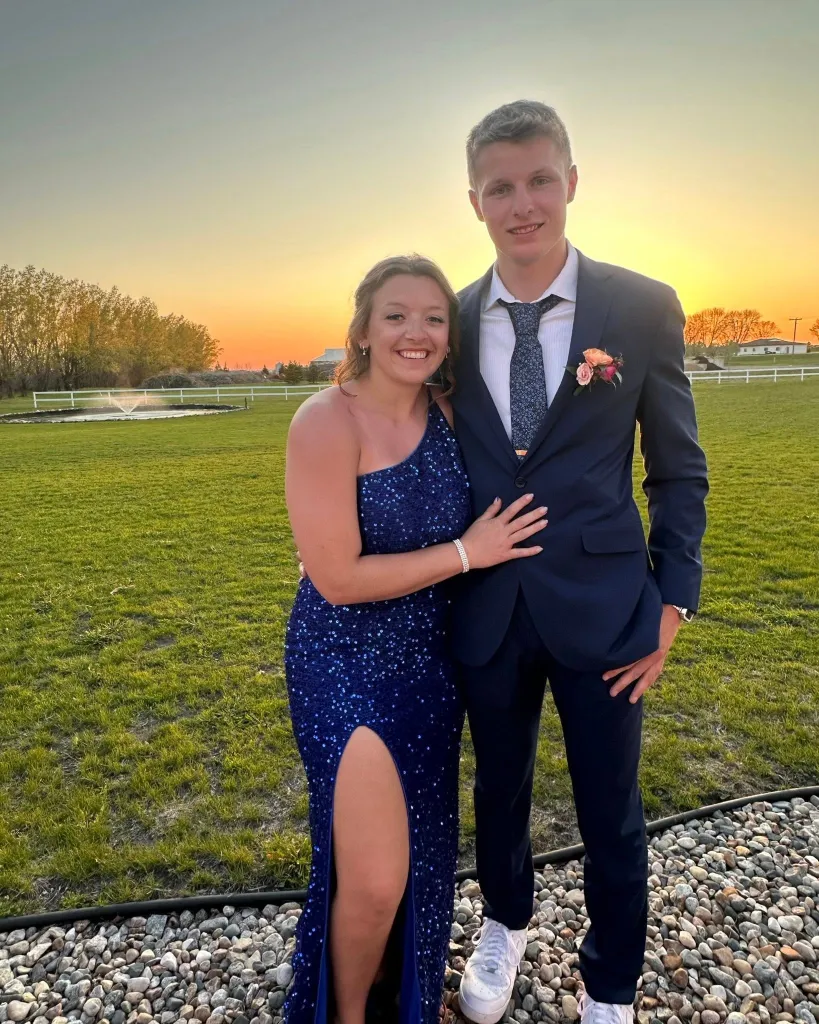 Couple in prom attire at sunset.