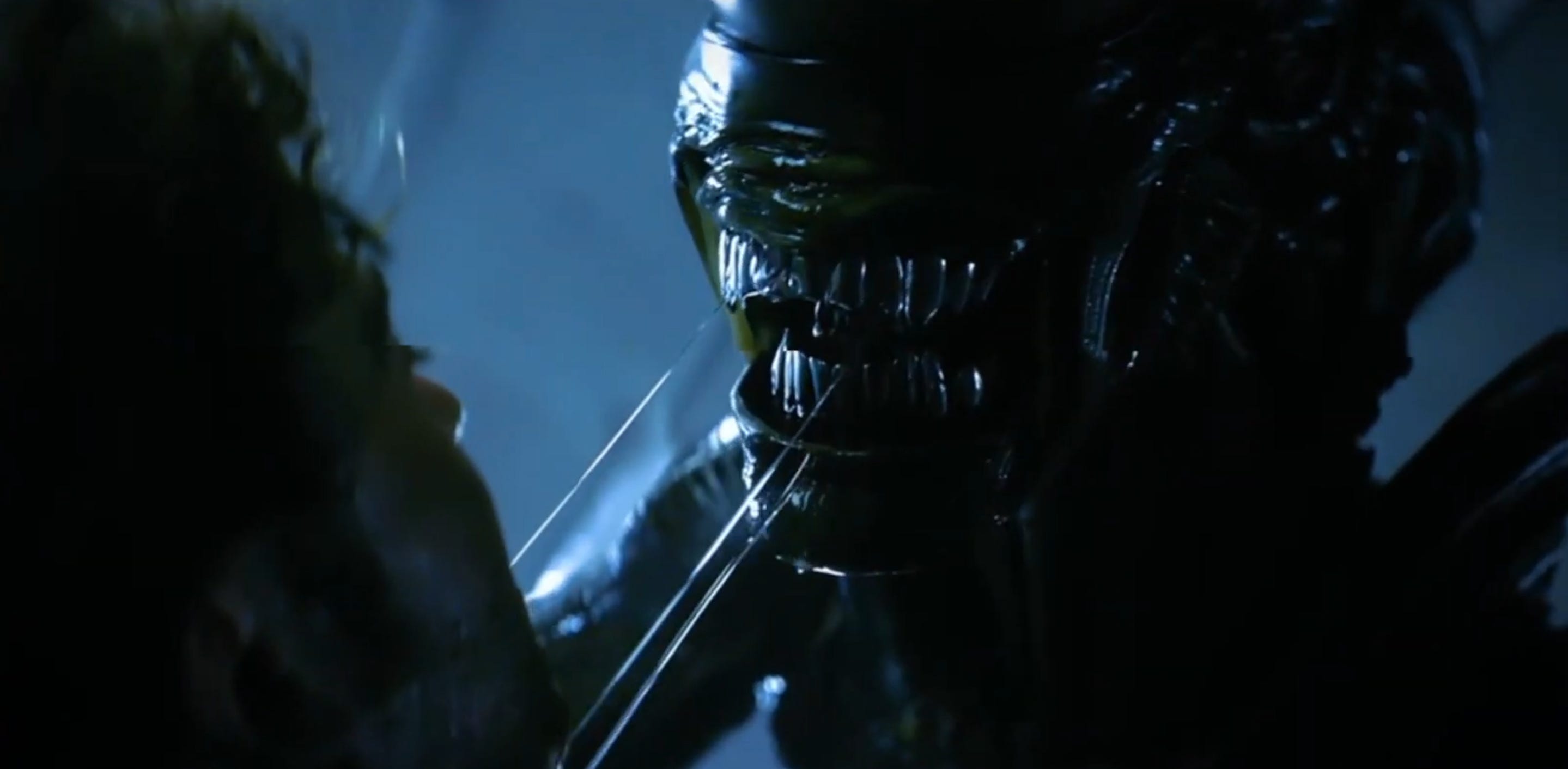 An Alien with sharp silver teeth is standing over a person while drooling on them.