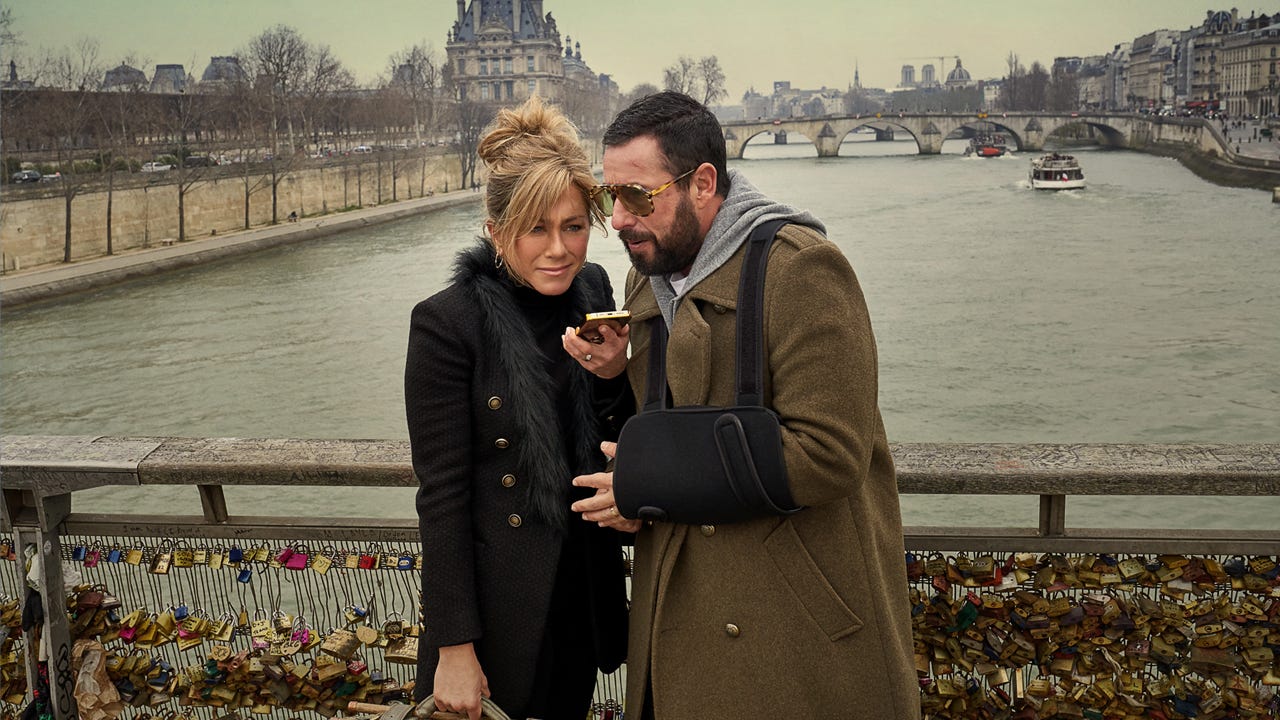 Jennifer Aniston and Adam Sandler speaking on a phone on a bridge