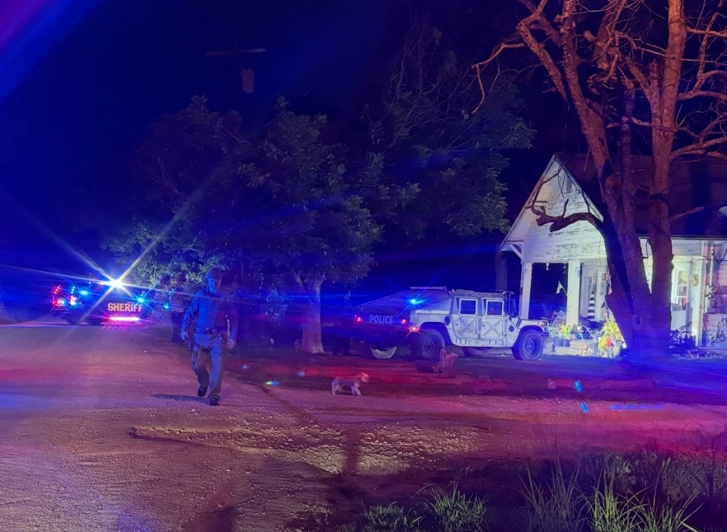 Nighttime photo of law enforcement officers at a house during a drug raid.