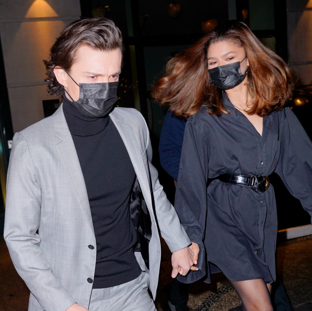 Tom Holland and Zendaya holding hands and wearing masks.