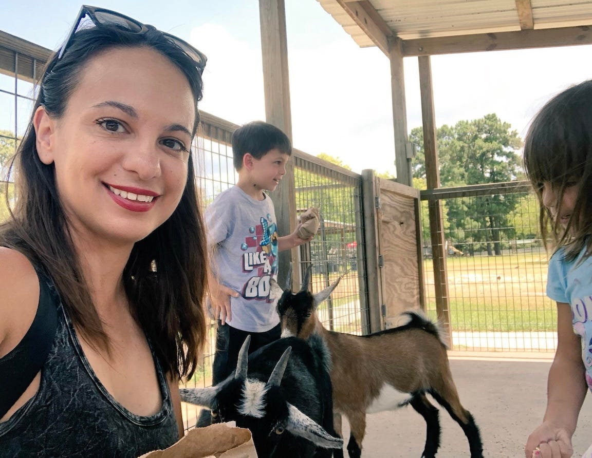 mother with two kids petting goats