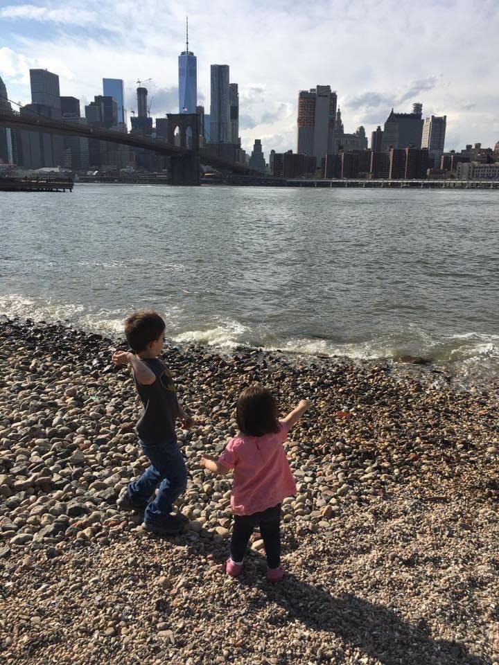 2 kids on beach in new york city with city skyline in background