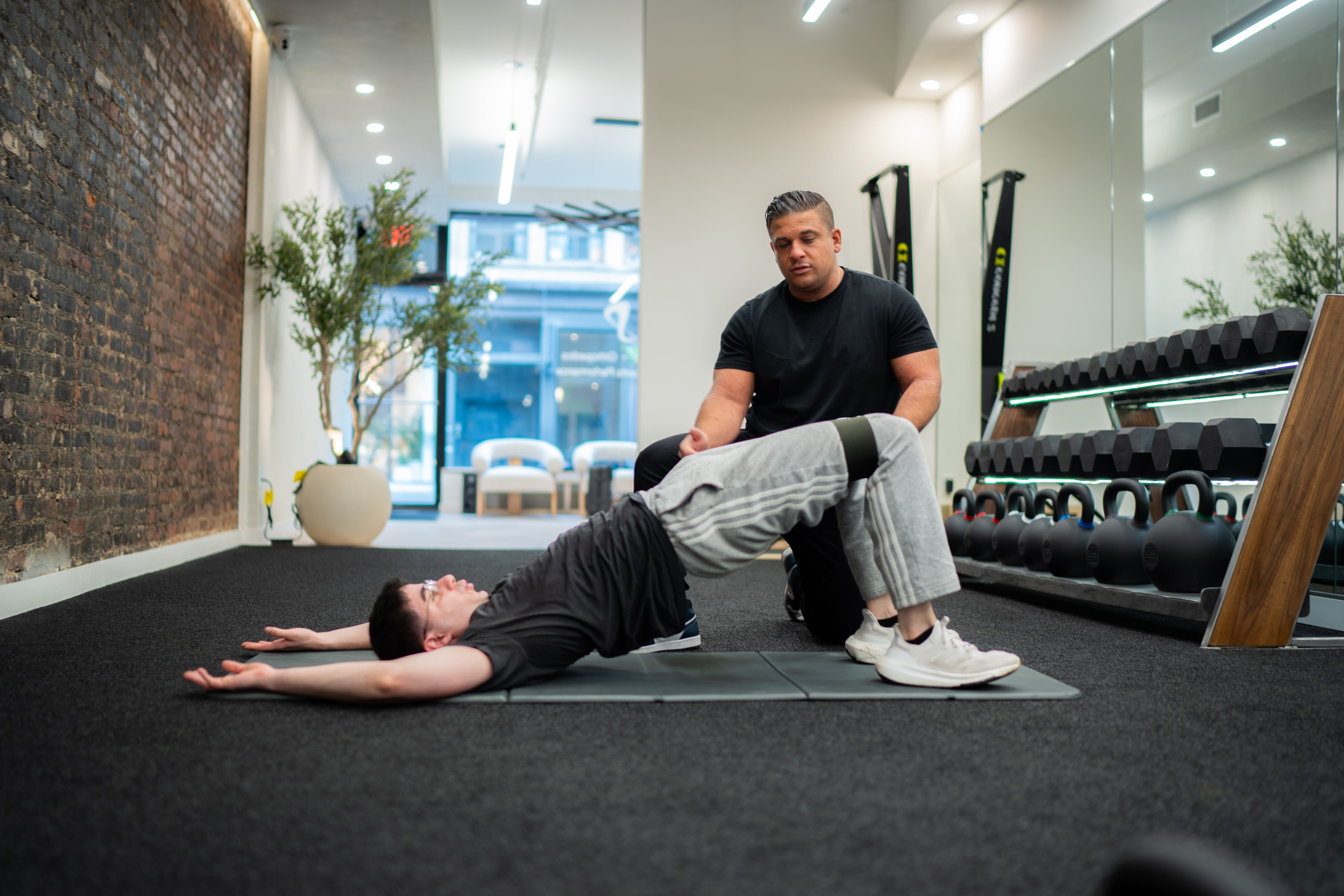 A physical therapist helps a patient bridge.