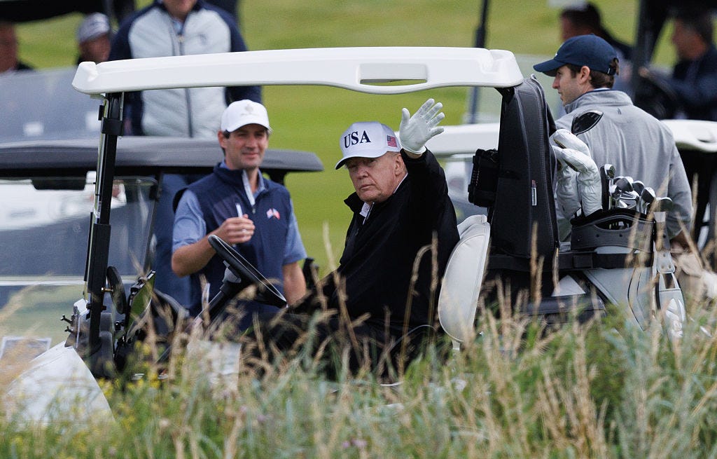 Donald Trump waves on a golf cart in Scotland.