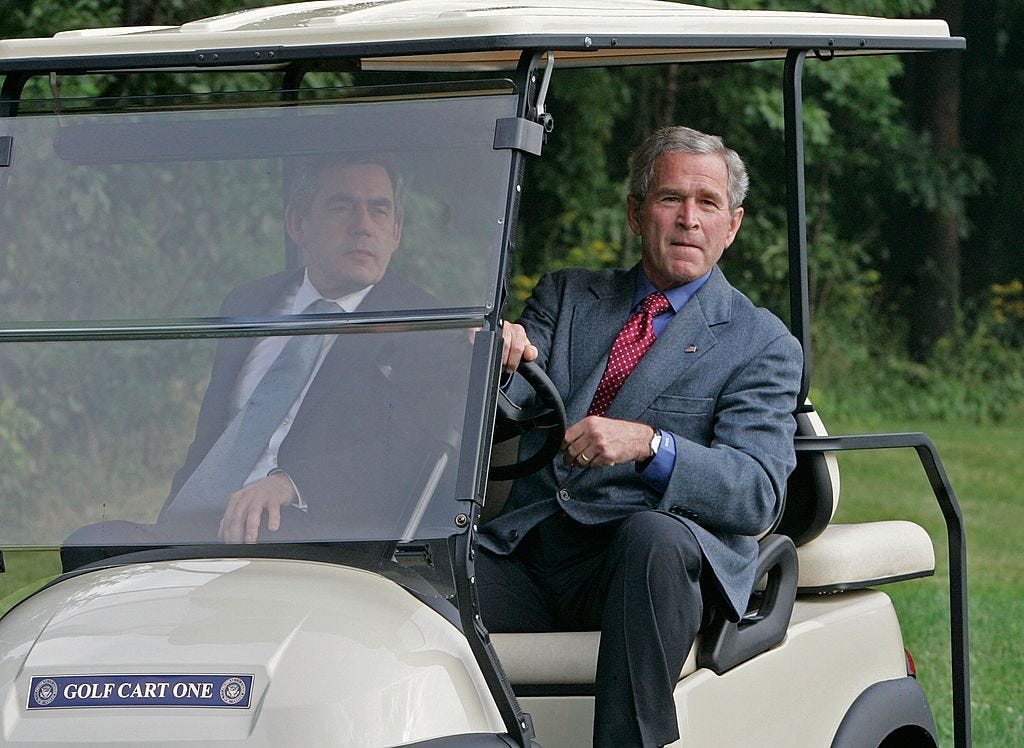 George W. Bush drives a golf cart at Camp David.