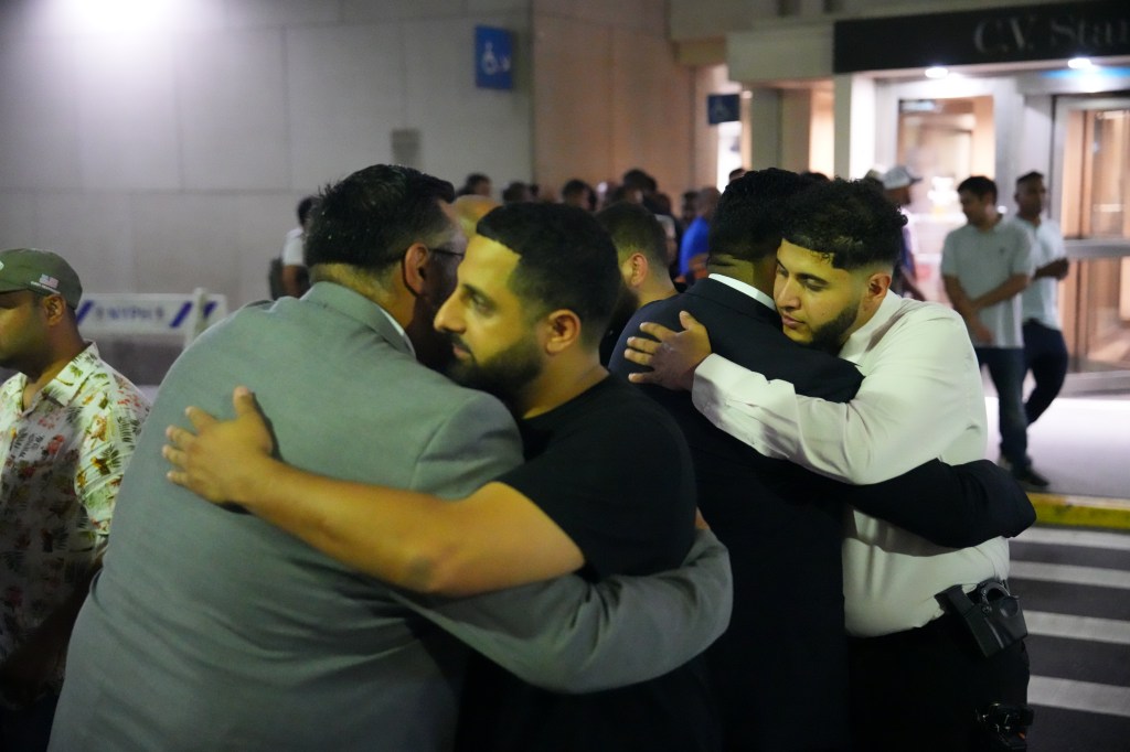 People embracing outside a hospital after a mass shooting.