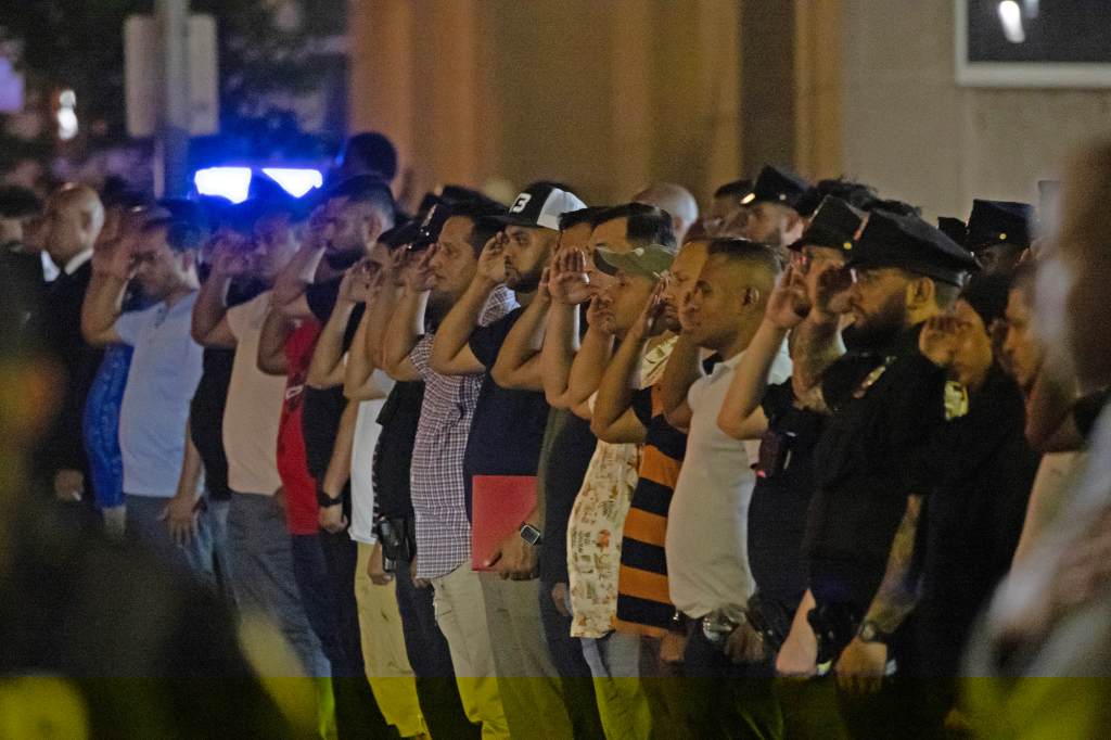 Police officers saluting during a dignified transfer of a fallen colleague.