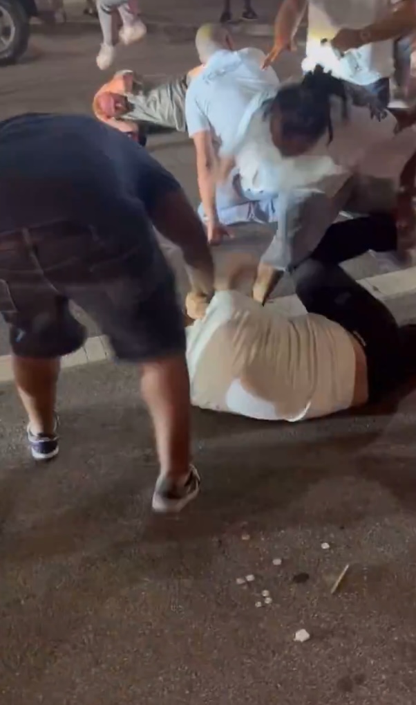 A person on the ground being restrained by others during a brawl.