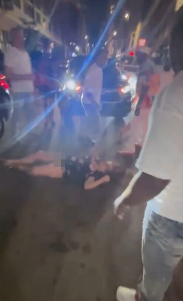 Footage of a woman lying unconscious on the ground after a fight.