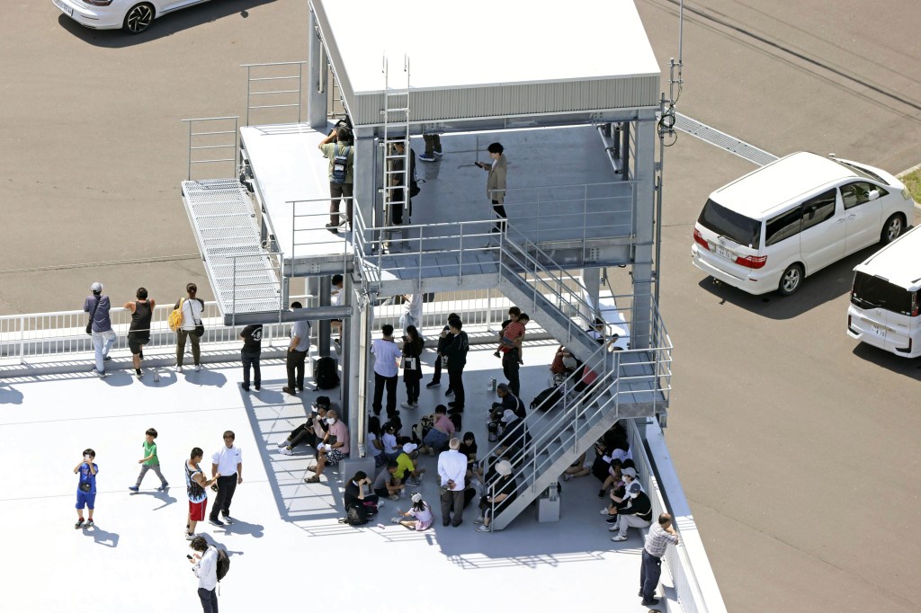 People take shelter on the roof of a fire station in Mukawa town, Hokkaido, northern Japan Wednesday, July 30, 2025, after a powerful earthquake in Russia's Far East prompted tsunami alert in parts of Japan.