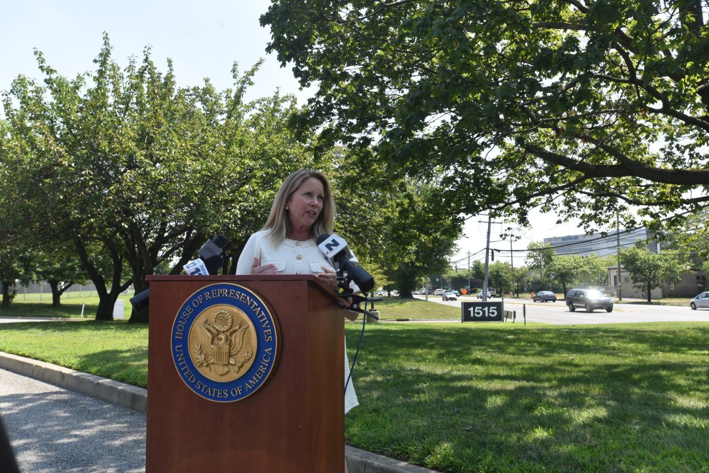 A woman speaking at a press conference podium.