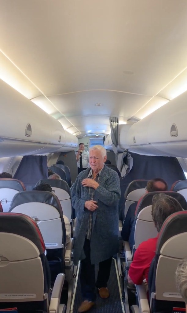 Elderly man walking down airplane aisle.