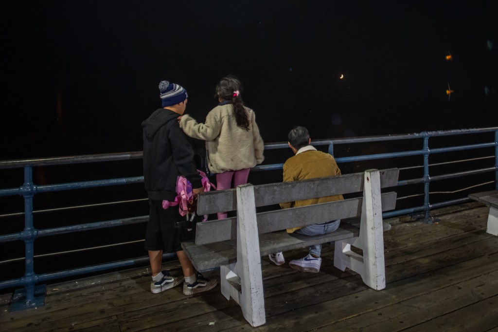 People sit on the Santa Monica Pier during a tsunami warning in Santa Monica, Calif. on July 29, 2025.