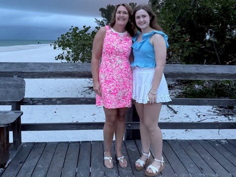 The author poses on a boardwalk at a beach with her daughter.