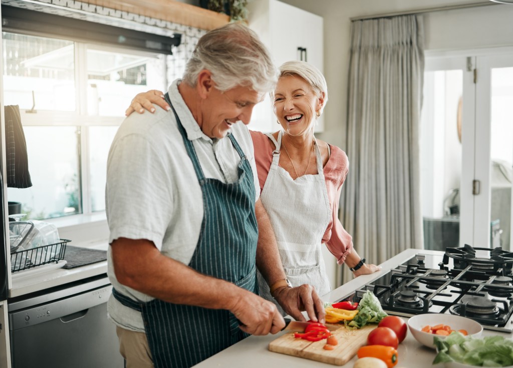 Happy senior couple preparing a vegan meal together in their kitchen.