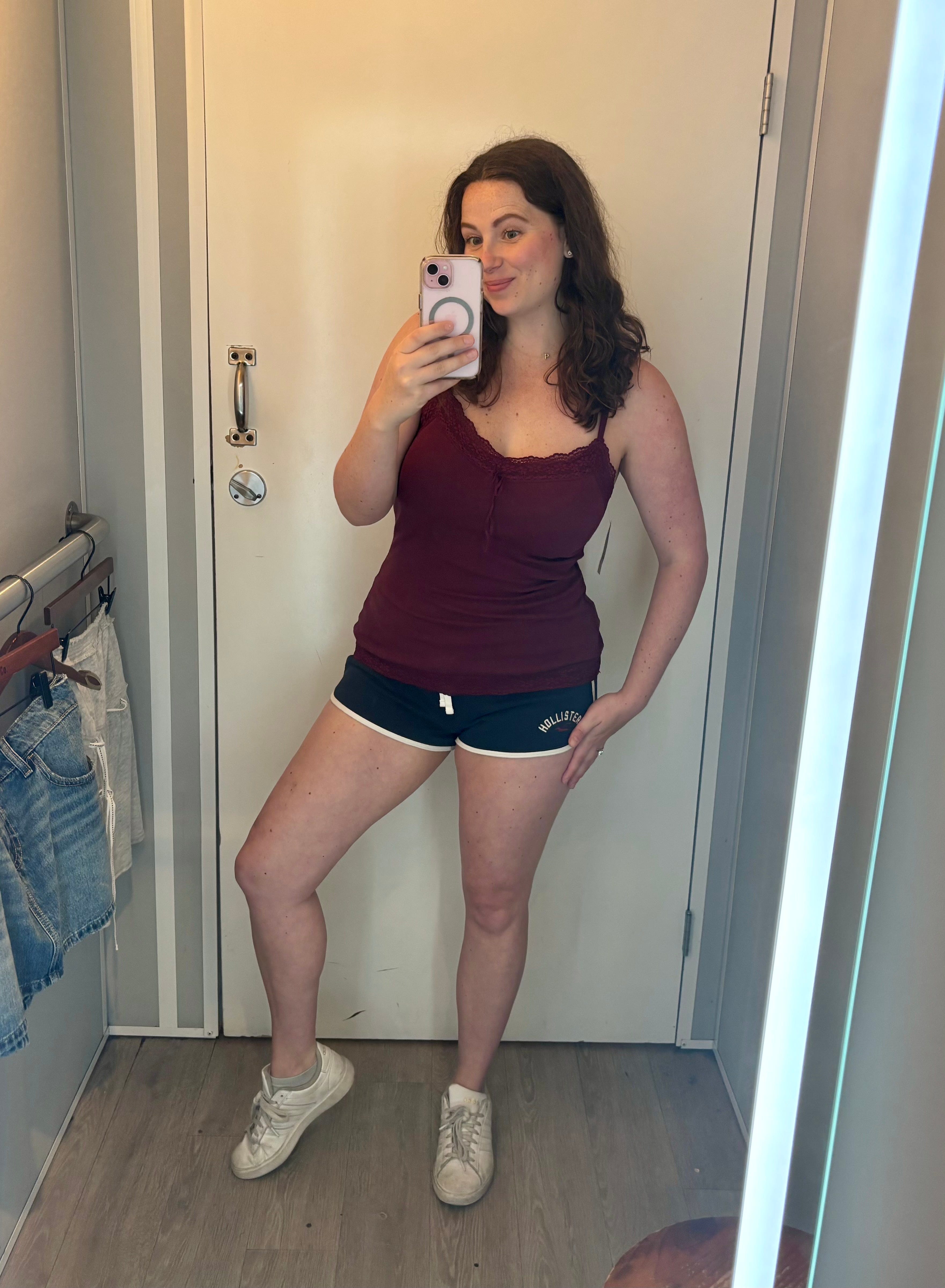 A woman tries on a tank top and shorts in a dressing room.