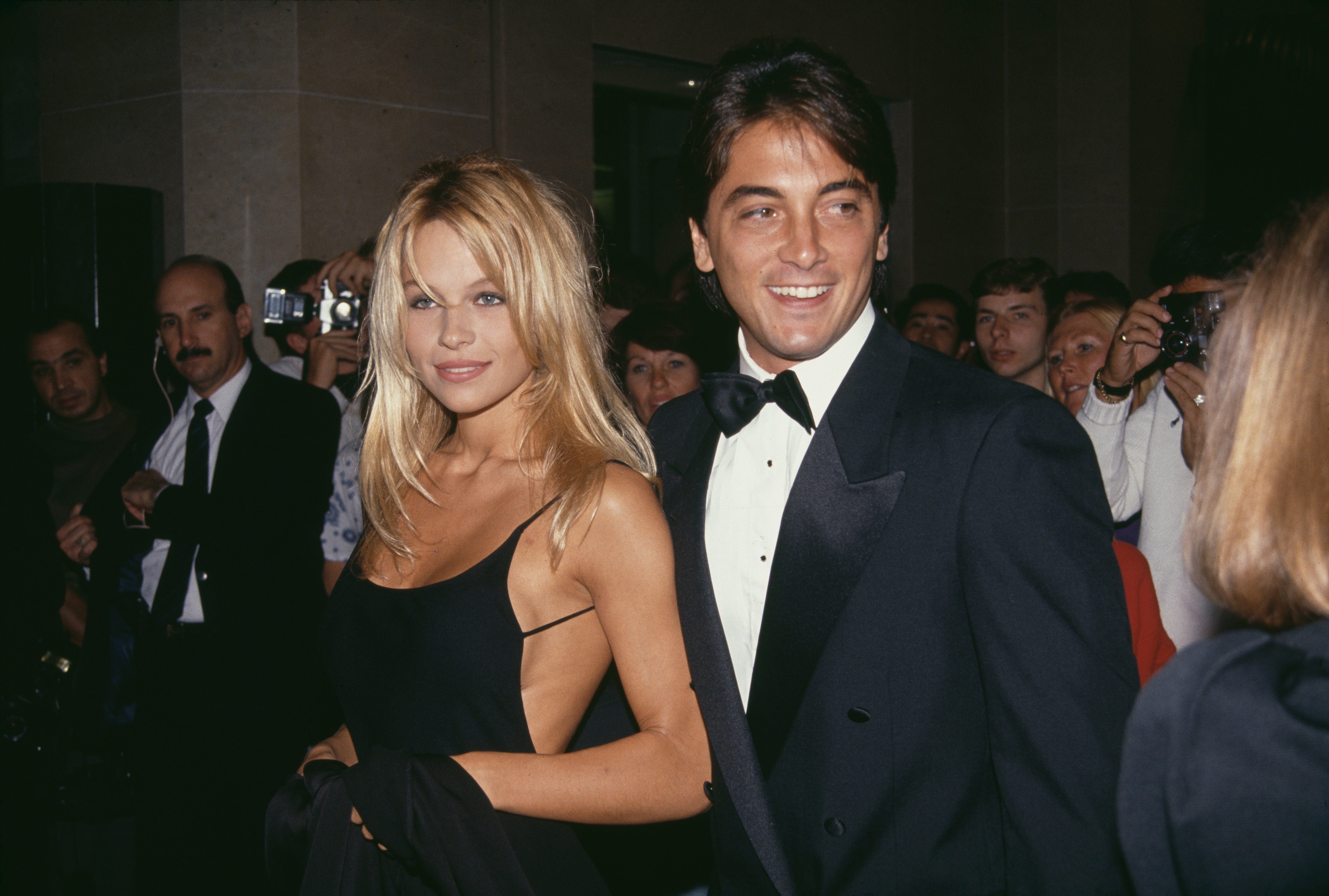 Pamela Anderson in a black dress next to Scott Baio in a tuxedo