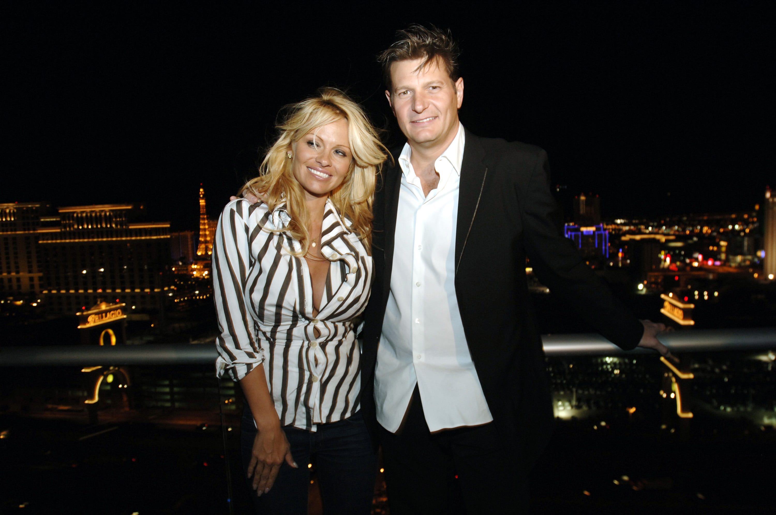 Pamela Anderson in a stripped shirt next to Laurence Hallier in a jacket and white shirt