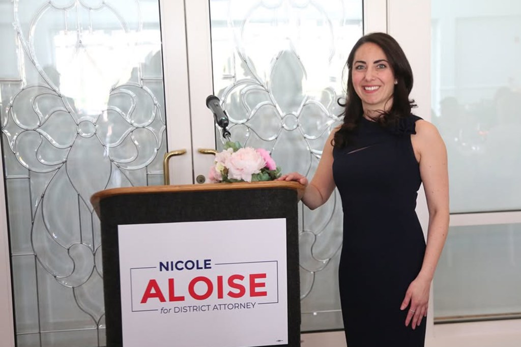 Nicole Aloise, candidate for District Attorney, standing at a podium.
