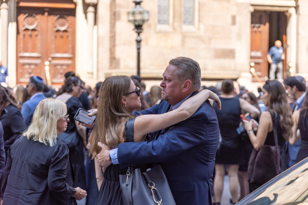Mourners embracing at a funeral.