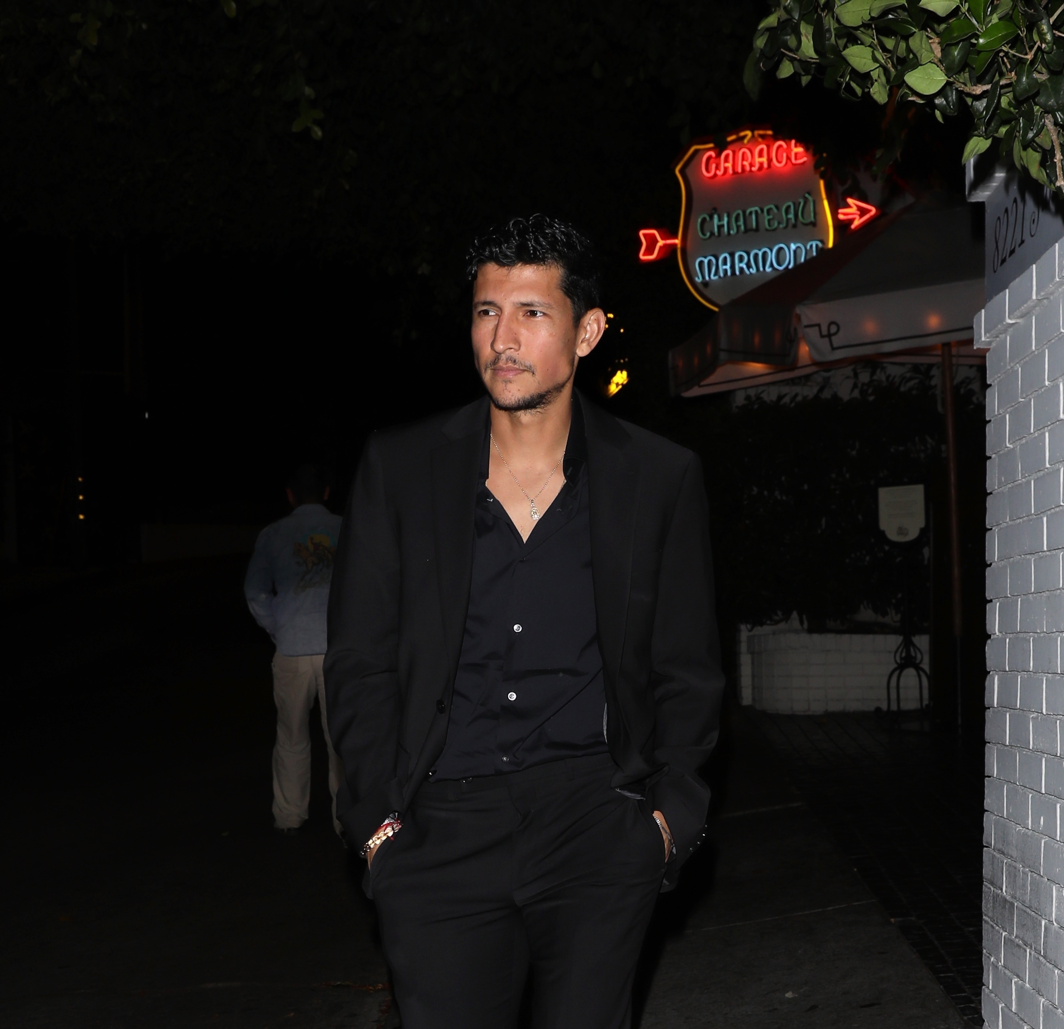 Danny Ramirez in black clothing in Los Angeles at night. 