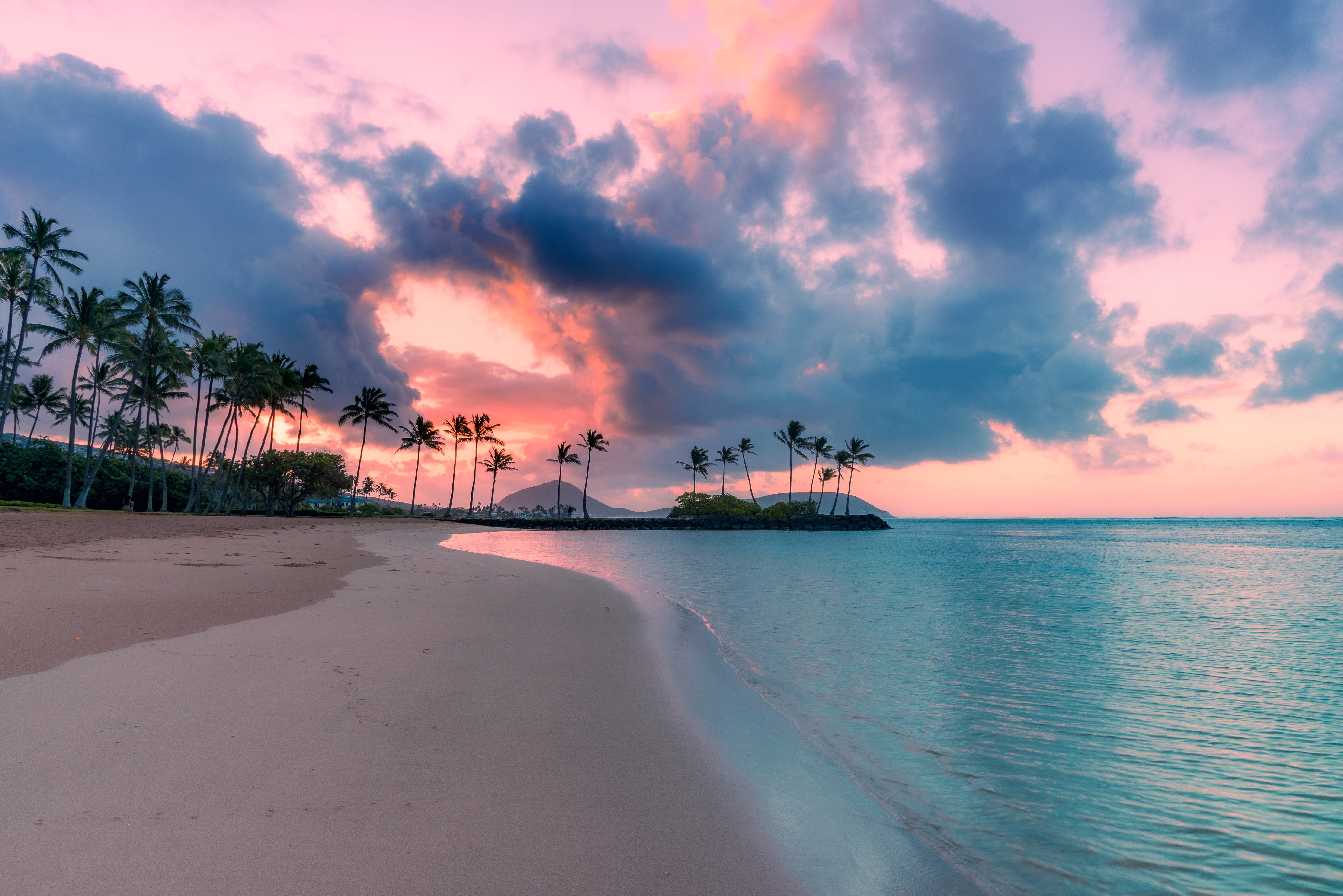 beach of tropical island at sunset with pink clouds and blue water