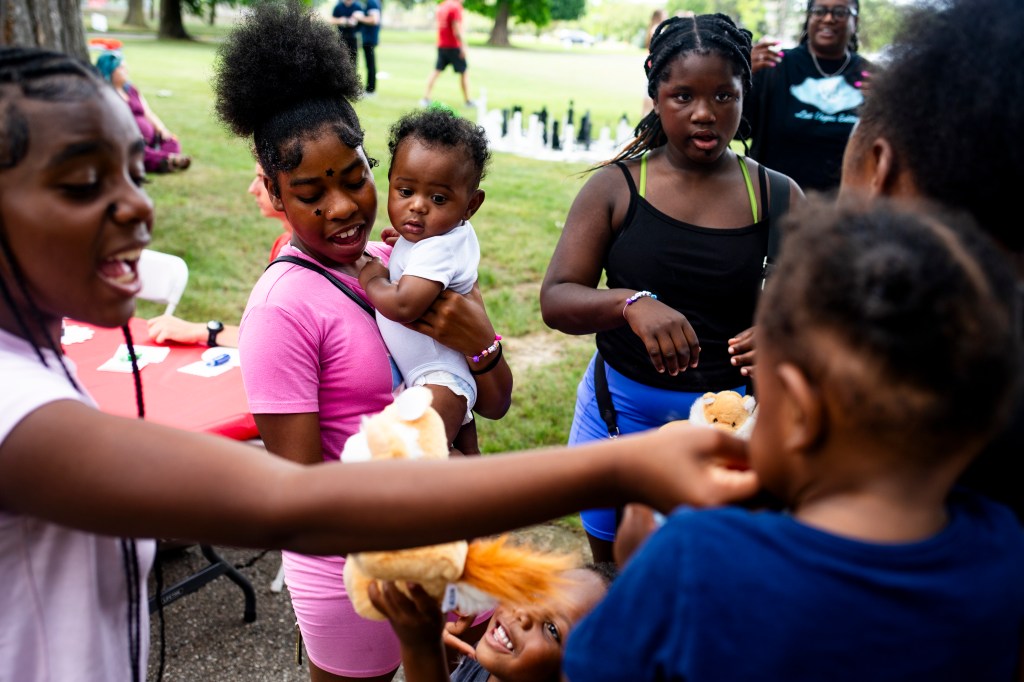Young girls at an outdoor event sharing stuffed animals.