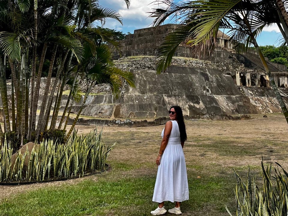 Author Lola Méndez smiling near stones, palm trees