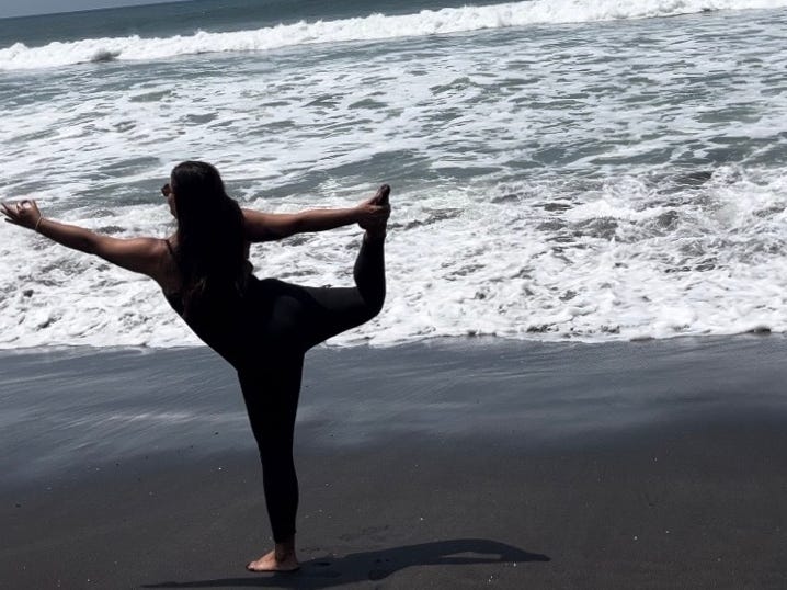 Author Lola Méndez doing yoga pose in front of waves
