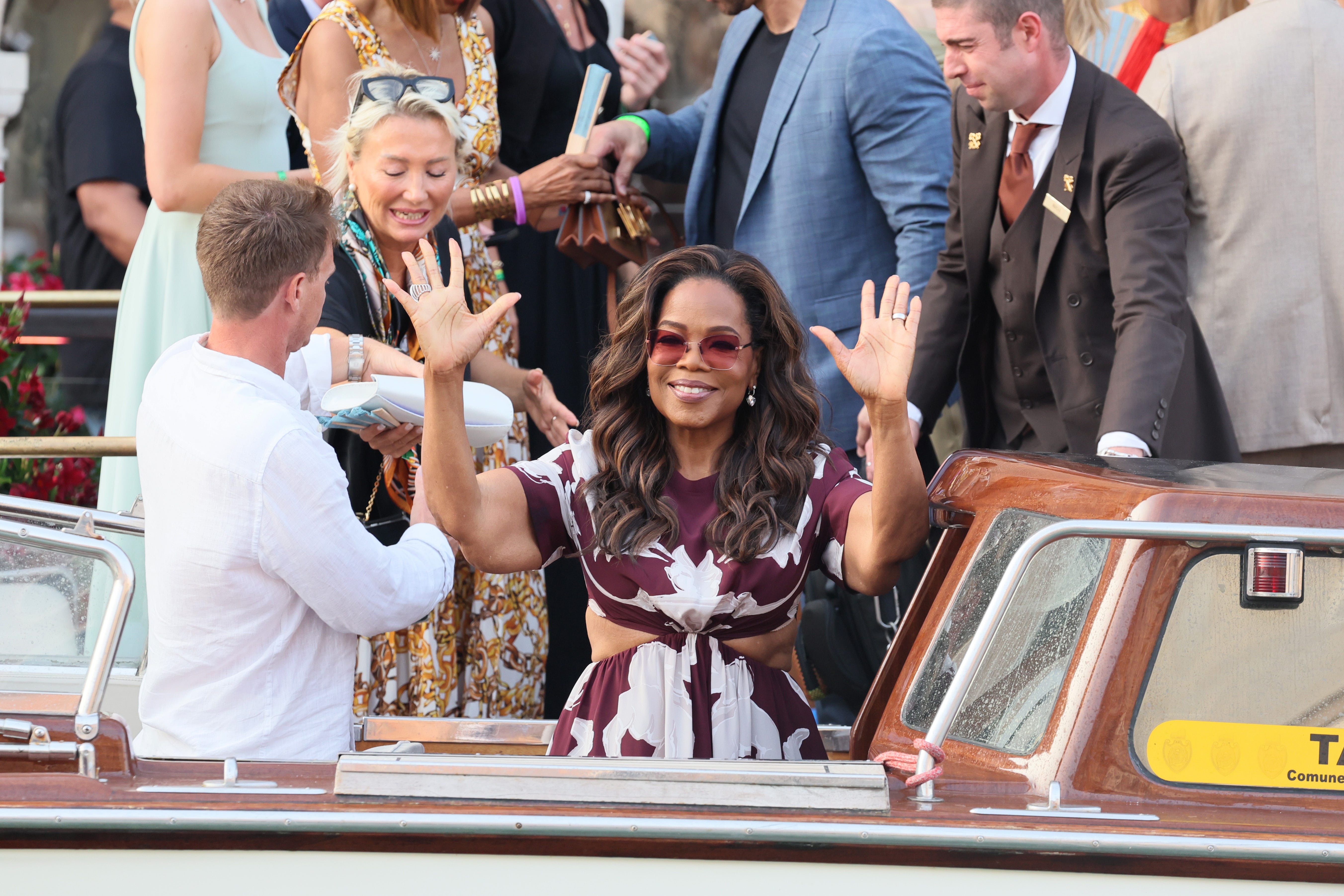 Oprah Winfrey waves at photographers from a water taxi in Venice.