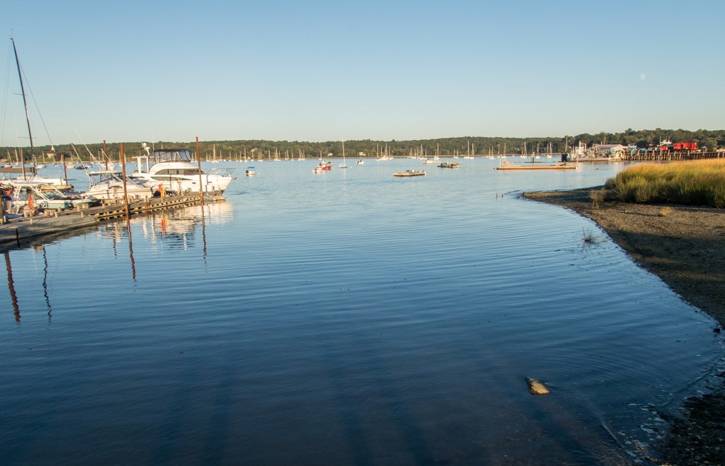 Sunset over Oyster Bay, NY, with boats docked at a marina.