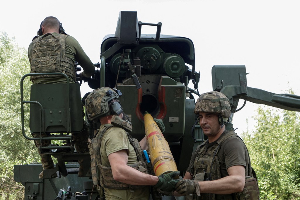 Ukrainian soldiers loading a shell into a self-propelled howitzer.