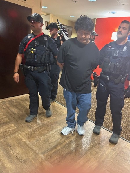 Suspect in custody, flanked by police officers.