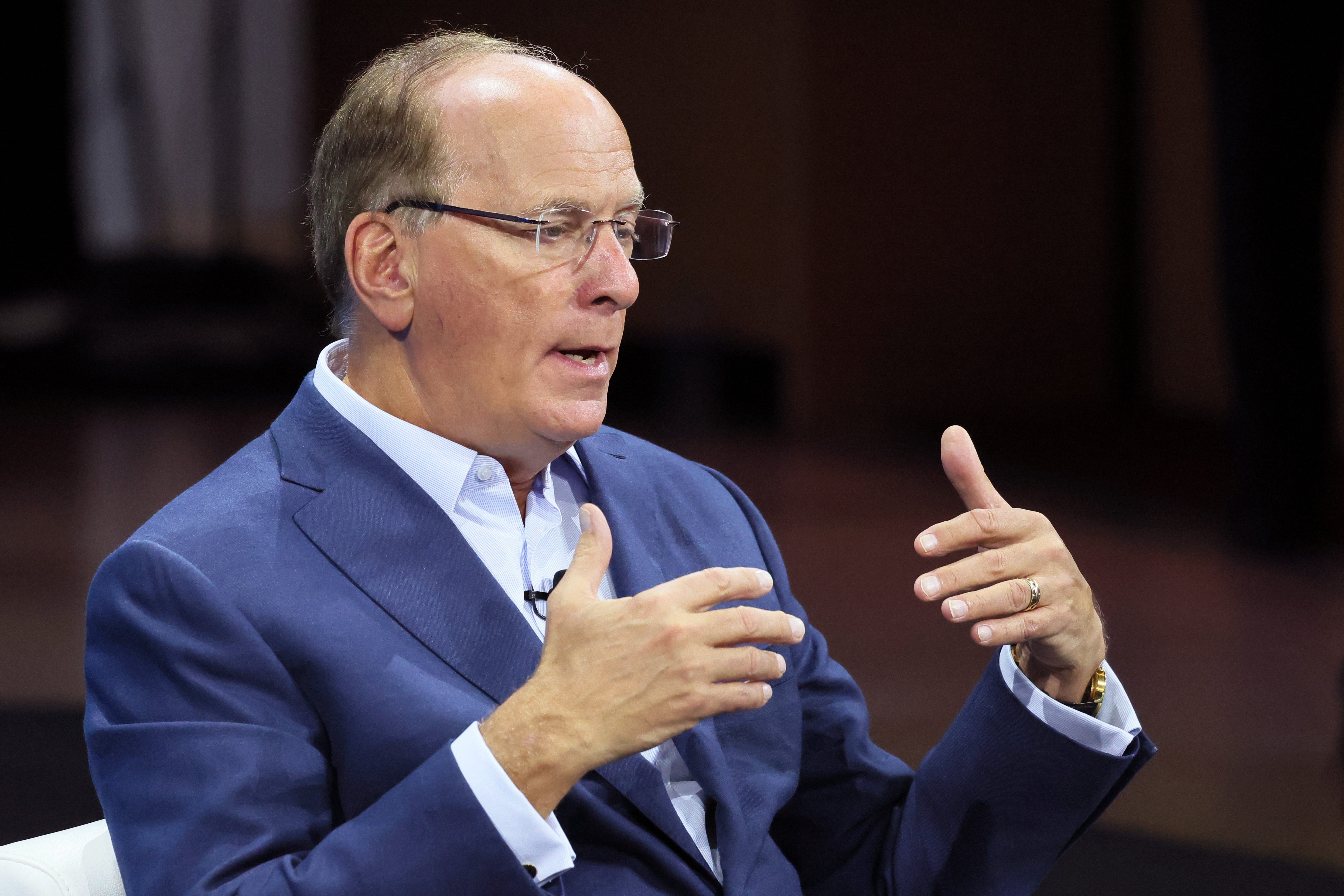 BlackRock CEO Larry Fink gesturing while wearing glasses and a suit jacket.