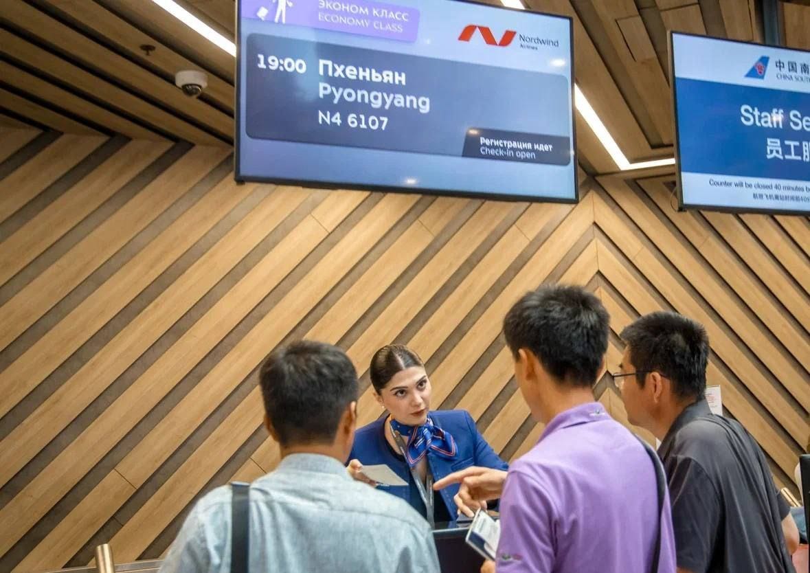 Passengers speak to service staff at an airport for a flight to Pyongyang.