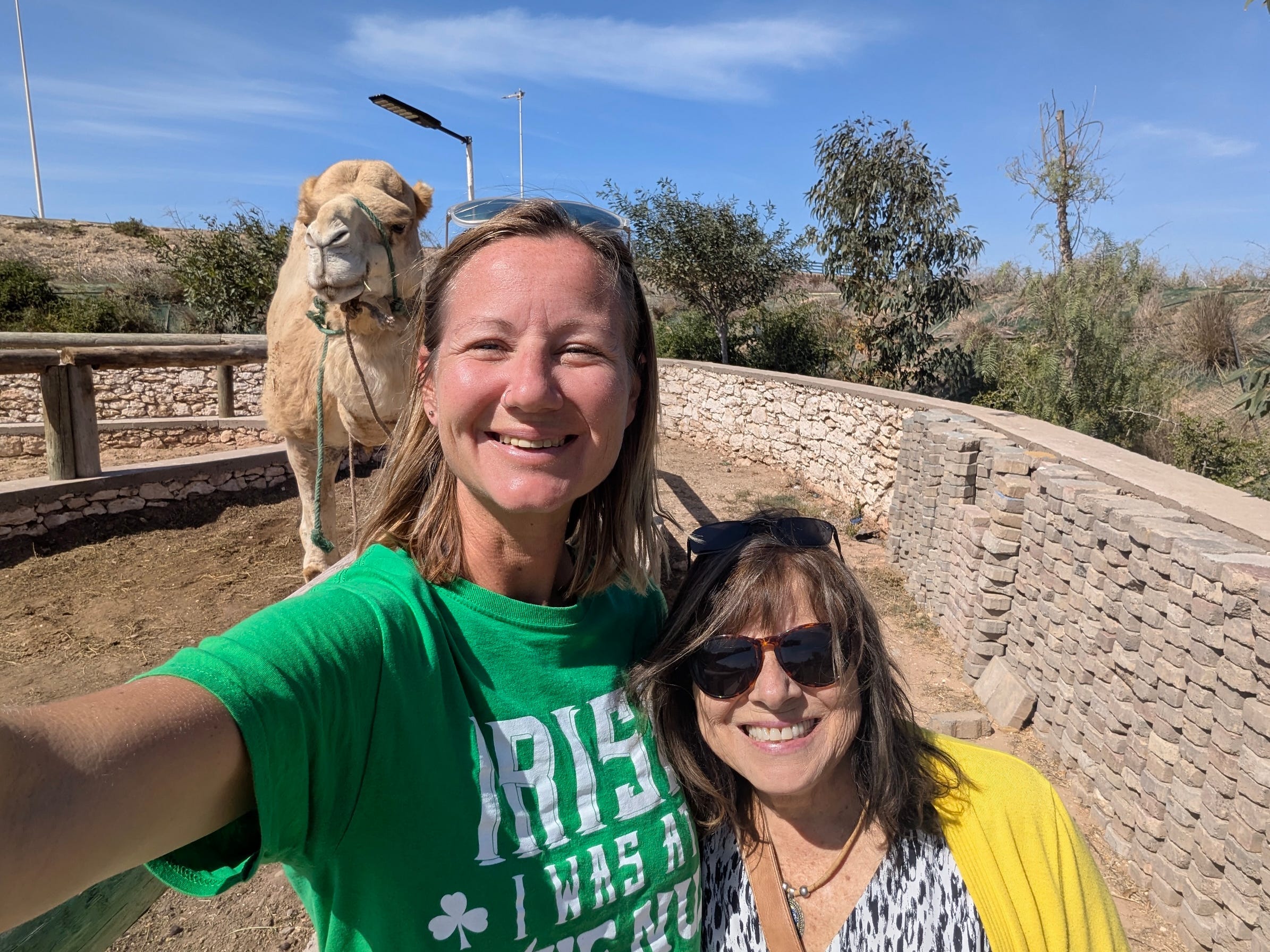 The author with her mother-in-law smiling in Morocco with a camel behind them.